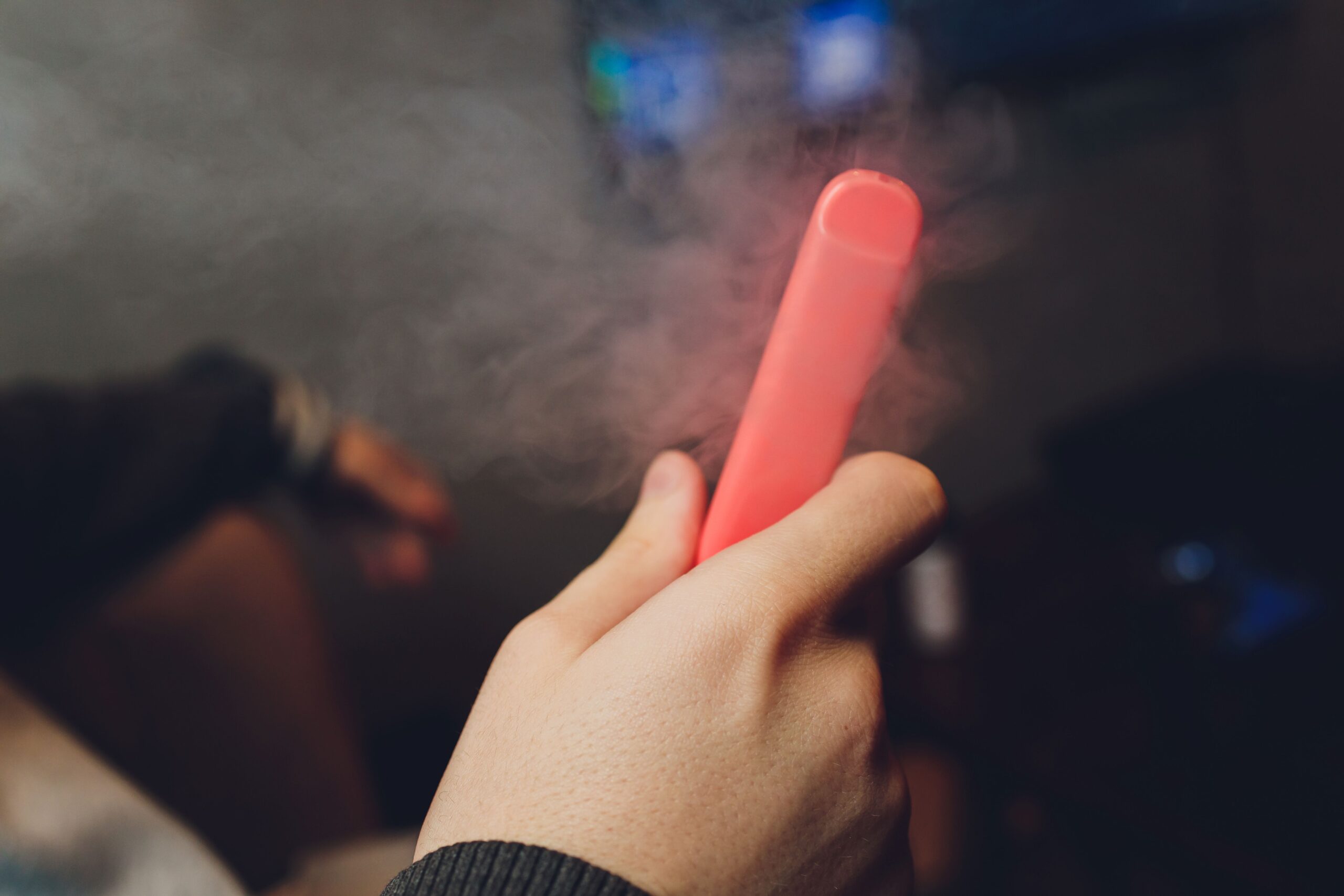 Eine Hand hält Elfbar Pods in dezentem Licht, während sanfter Dampf aufsteigt