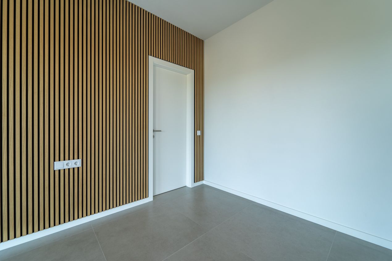 Vertikal montierte Akustikpaneele aus Holz an einer Wand verbessern die Raumakustik und unterstützen eine moderne Arbeitsplatzgestaltung